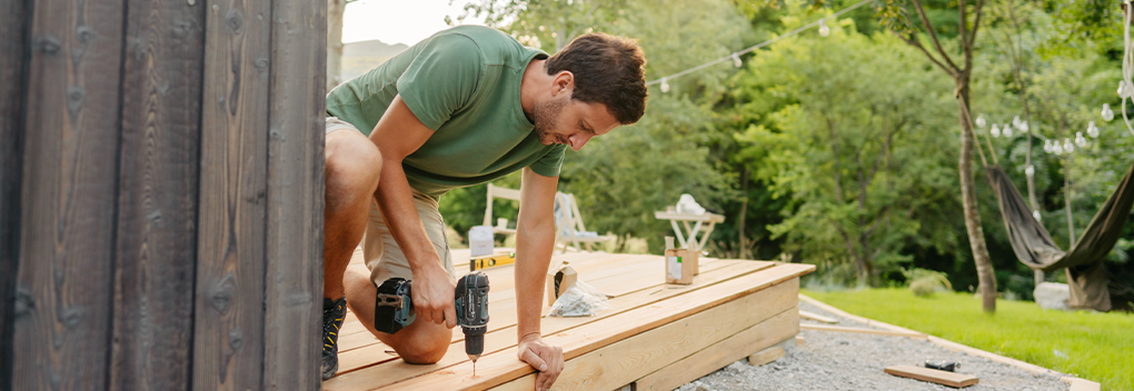 Man outside with drill working on a home improvement project.